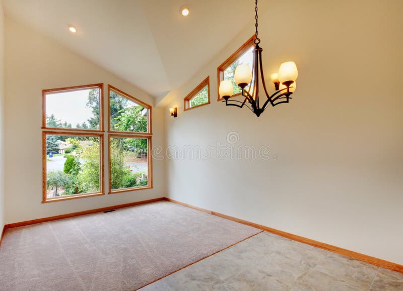 Empty room interior in beige tones with large window and vaulted ceiling. Empty room interior in beige tones with large window, chandelier, carpet floor and stock image