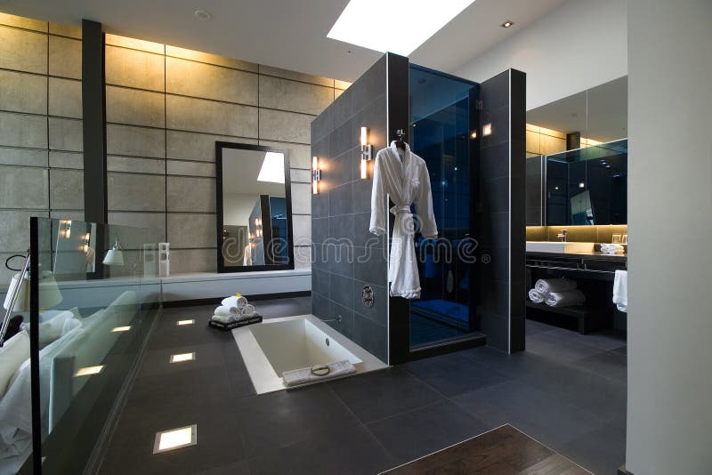En suite bathroom with dark grey tiles. Bath and shower stock photos