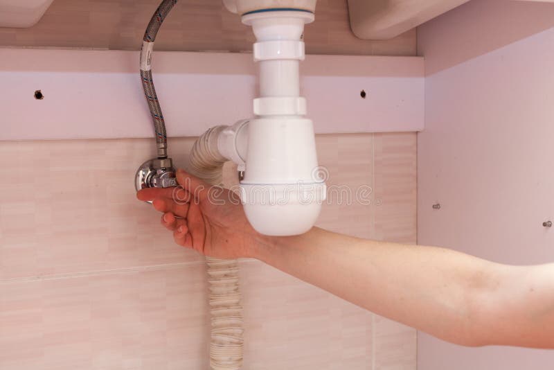 Exposed plastic plumbing attached to a copper joint with a shut-off valve under a white sink. Shut off the water supply to the sin. K in the bathroom royalty free stock photography