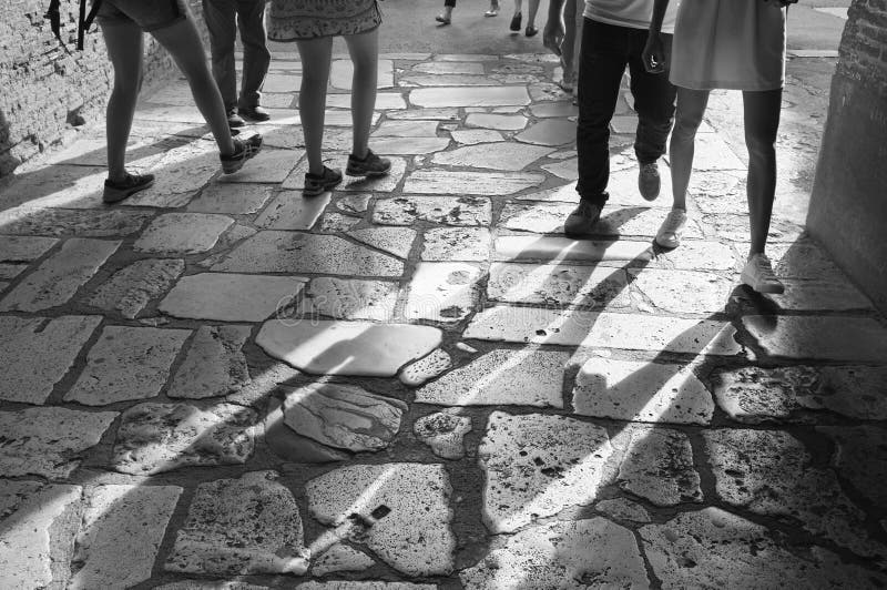 Feet walking on travertine floor in the Colosseum in Rome. Several pairs of feet walking on the travertine floor of the Colosseum in Rome, Italy casting long stock image