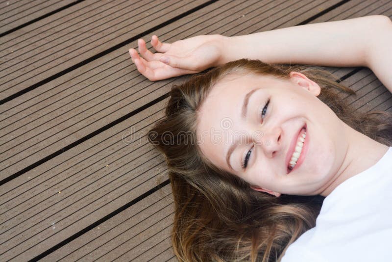 Female teenager smiling, layingon the floor. Summer, portrait of young girl with long, blonde hair stock image