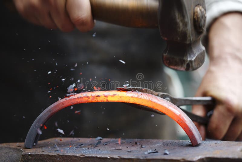 Forging hot iron. Detail shot of hammer forging hot iron at anvil stock image