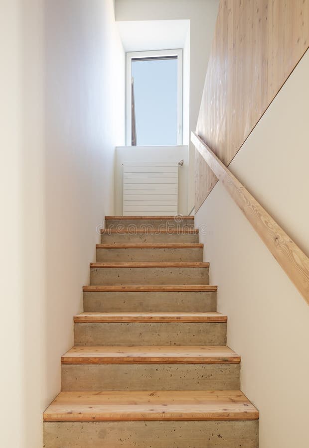 Front view of stairs in raw wood. At the top of the staircase there is a window. With a view of the blue sky. No one inside stock photography