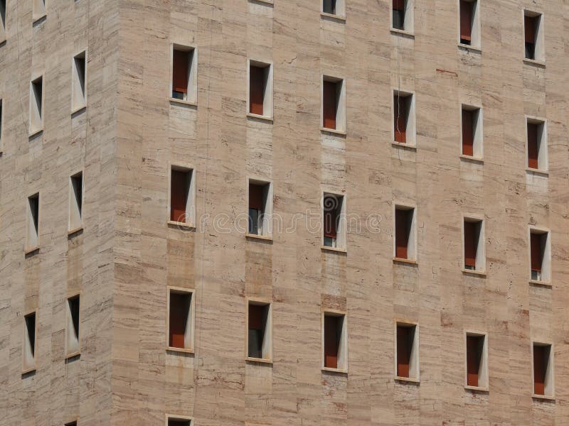 Geometric windows on facade of modern rationalist style building. Beige travertine marble cladding. Rome, Italy stock photos