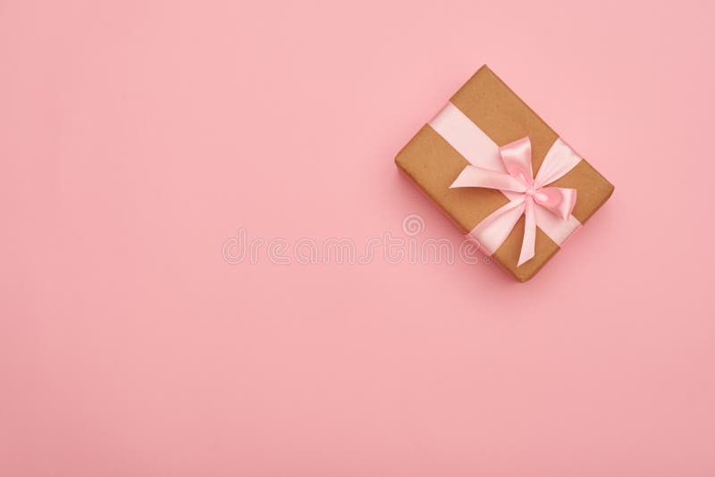 Gift box with pink bow placed at the right corner on pink flatla. Top view of gift box with pink bow placed at the right corner on pink flatlay royalty free stock image