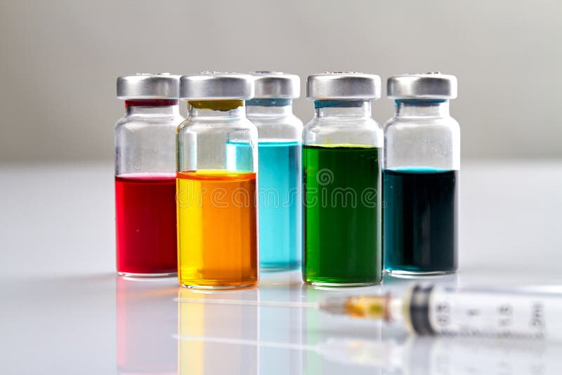 Glass vials with colored medicine liquid and syringe. royalty free stock image