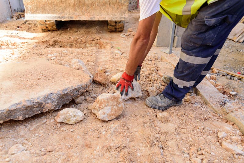 Gloved worker removes a rock from the road on a construction site stock images