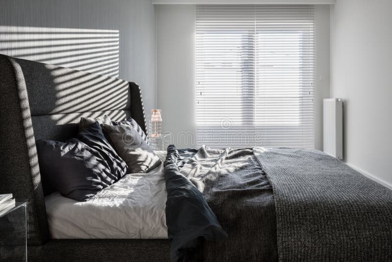 Gray bedroom with window blinds. Sunny, gray bedroom with double bed and window with long blinds stock photos