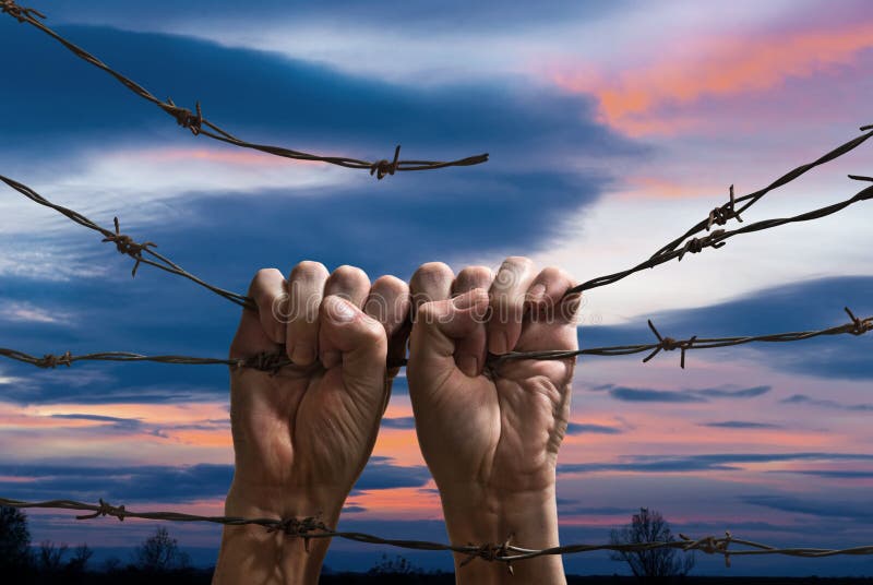 Hand behind barbed wire. Hands behind barbed wire with sunset in the background stock photos