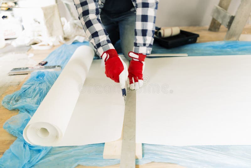 Handyman, worker measuring wallpaper to cut. Home renovation and repair concept stock images