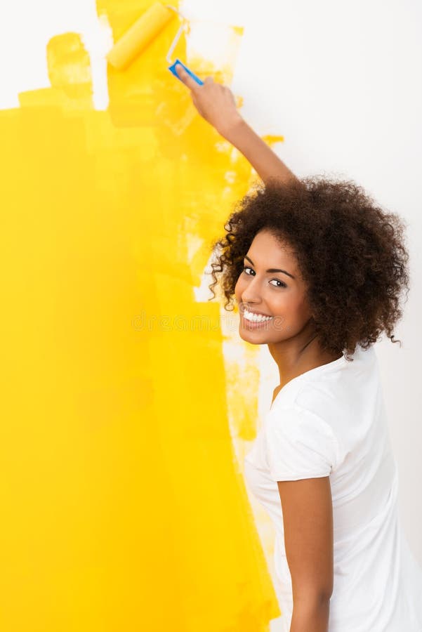 Happy young woman painting a wall orange stock photos
