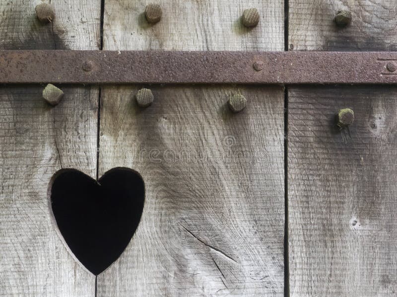 Heart carved in wood. Heart as a cutout in the wooden door of a toilet house royalty free stock photography