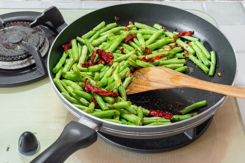 Home cooked food. French green beans, dried chillies and garlic in stir-fry pan on cooking stove. French green beans, dried chillies and garlic in stir-fry pan royalty free stock photo