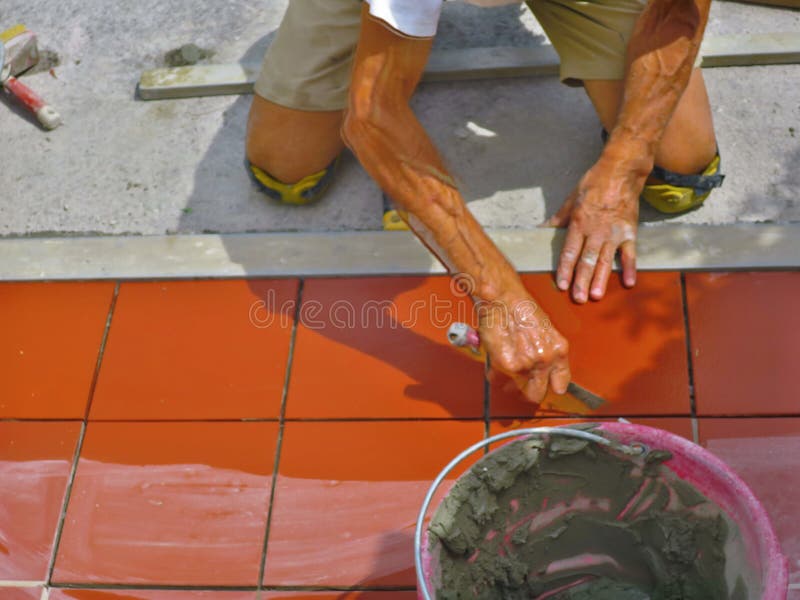 Home improvement, renovation - construction worker tiler is tiling, ceramic tile floor adhesive.  stock photography