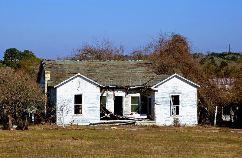 House in Need of Repair. Damaged house with roof caving in and missing windows could illustrate storm or fire damage remodeling insurance needs etc stock photos