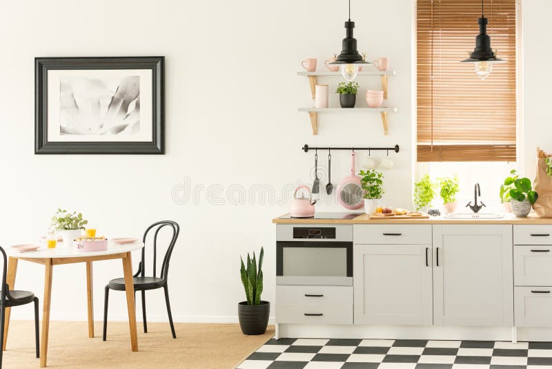 Industrial lamps and black dining chairs in a white kitchen interior with a modern oven and breakfast food. Concept photo stock photo