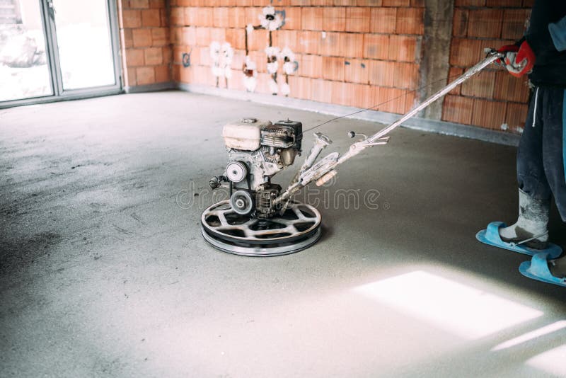 Industrial worker finishes concrete screed with trowel machine. Worker finishes concrete screed with trowel machine stock photo