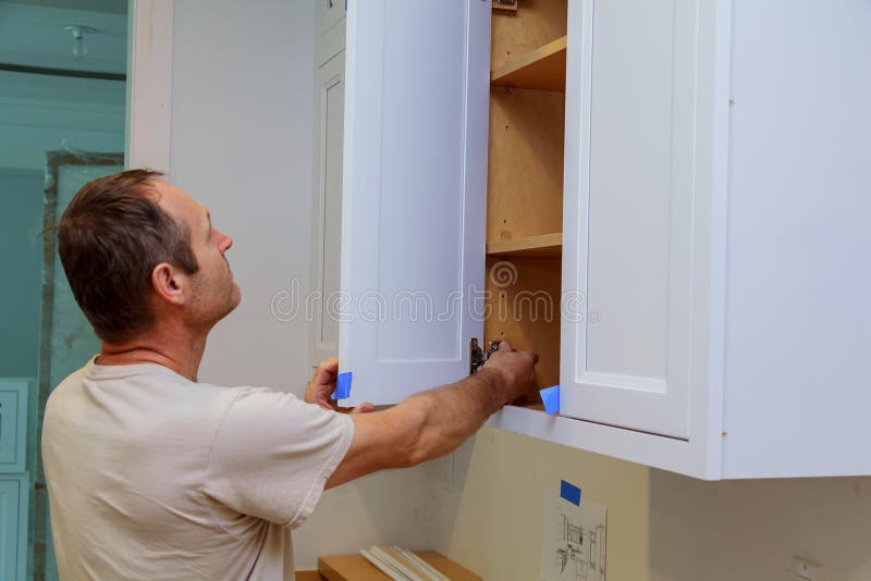 Installation kitchen. Worker installs doors to kitchen cabinet. royalty free stock image