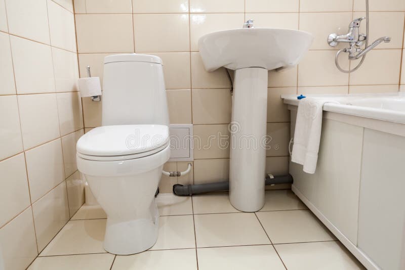 Interior of simple half bathroom with toilet, sink and bath with shower, white sanitary ware. Interior of simple half bathroom with toilet, sink and bath with stock images