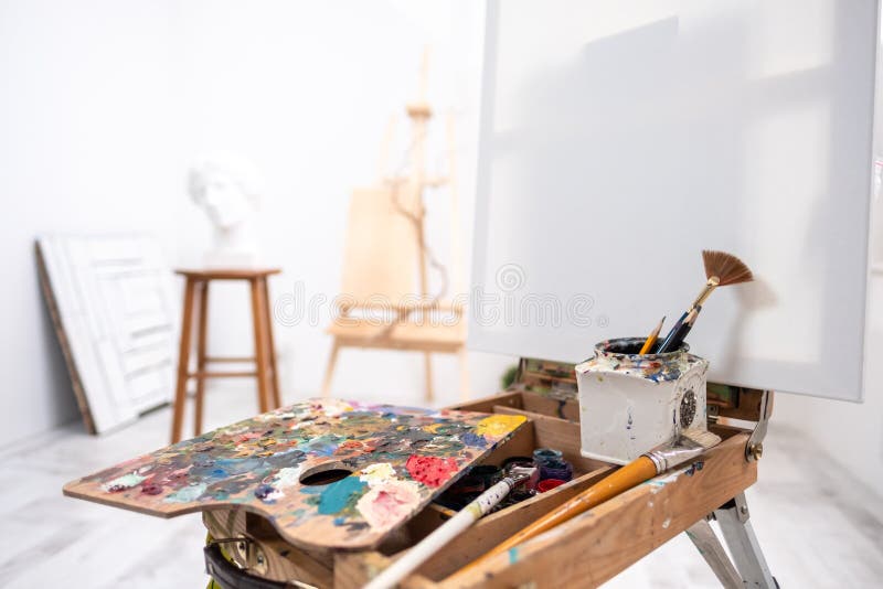 Interior of white studio of the artist, creative person. Easel, brushes, plaster head and figures. Attic, high ceilings. Daylight royalty free stock photo