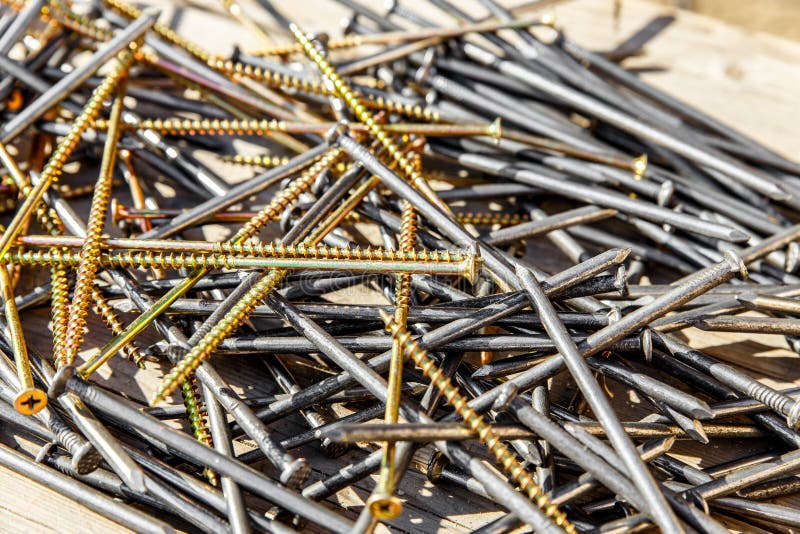 Iron nails and screws on a wooden background. Long, metal, carpenter`s nails and self-tapping screws for construction. Fixing too royalty free stock photos
