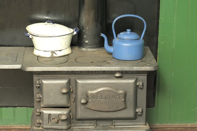 Kettle and pot on a coal stove. Blue kettle and white pot on a coal stove stock photos