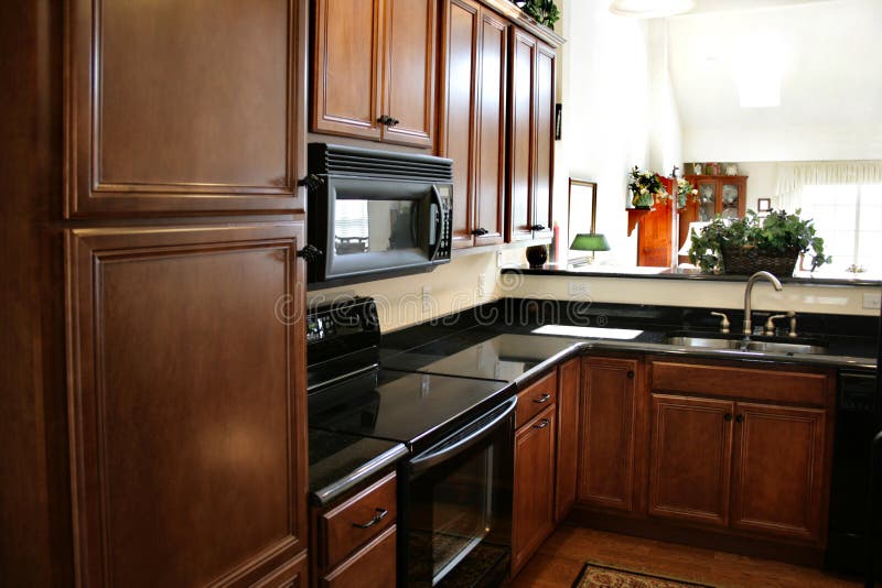 Kitchen wood cabinets black and stainless stove royalty free stock images