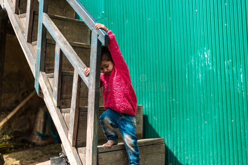 Kullu, Himachal Pradesh, India - September 01, 2018 : Himalayan kid at Stairs of traditional wooden house in mountain royalty free stock images
