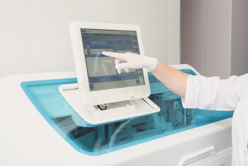Lab tech loading samples into a chemistry analyzer stock images