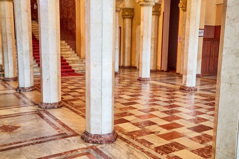 Large hall with white columns and a square checkered red tile pattern on the floor royalty free stock images