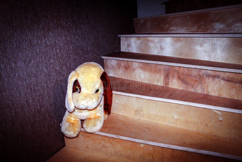 On a wooden staircase leading to the second floor of a residential building, there is a soft toy for small children stock photo