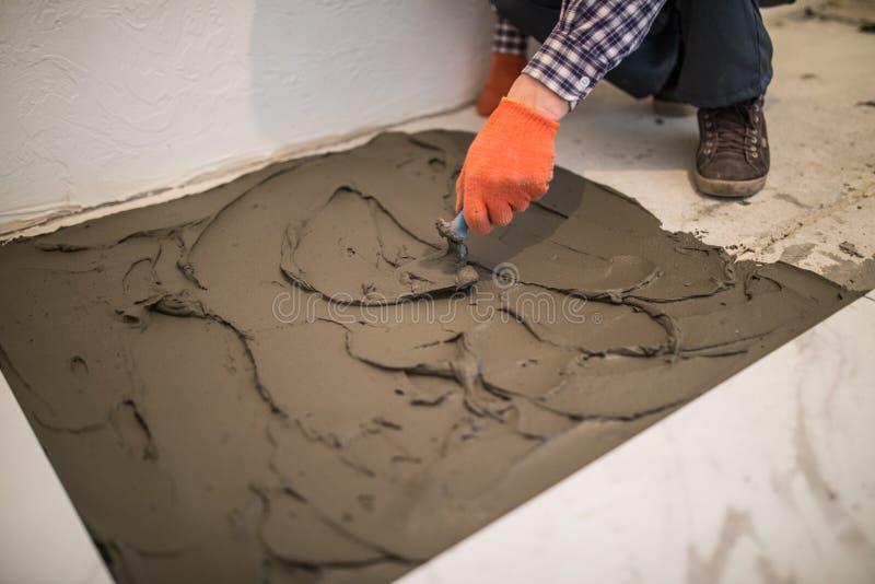 Laying Ceramic Tiles. Master make concrete floor in preparation for laying floor tile. Laying Ceramic Tiles. Troweling mortar onto a concrete floor in stock photography