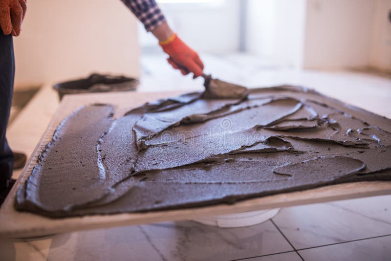 Laying Ceramic Tiles. Worker make preparation for laying floor tile. Laying Ceramic Tiles. Troweling mortar onto a concrete floor in preparation for laying royalty free stock images