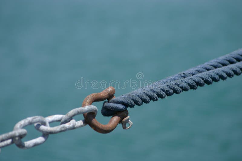 Linking. The rope of a yacht linked by a hook to a chain stock image