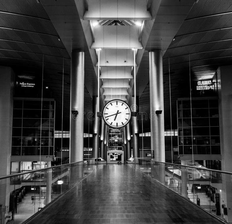 Low angle grayscale view of a modern building hall with a clock hanging from the ceiling royalty free stock images