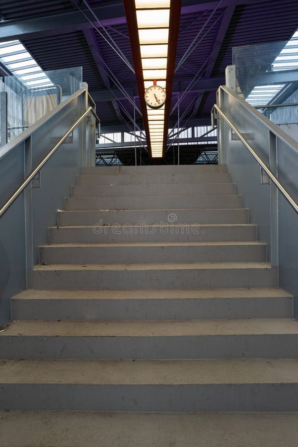 Low angle view of industrial stairs leading to top mounted analog clock in a train station royalty free stock photos