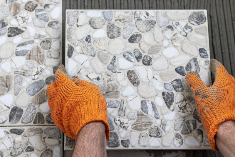 Male hands with tile and glue on wall. Work of laying tiles. stock images