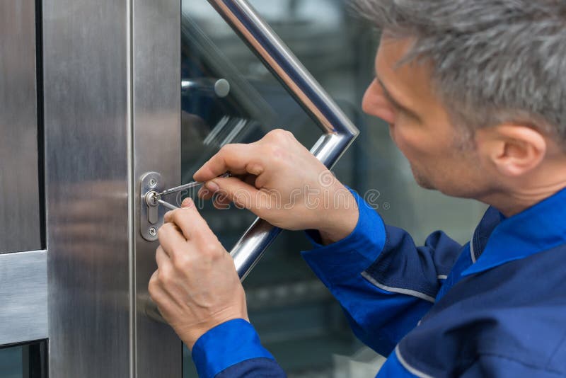 Male Lockpicker Fixing Door Handle At Home. Mature Male Lockpicker Fixing Door Handle At Home stock photo