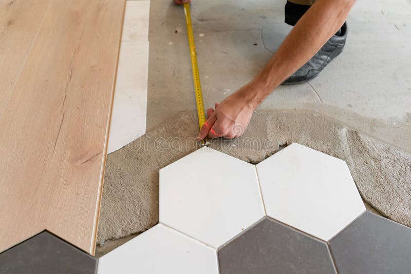 Male worker installing new wooden laminate flooring on a warm film floor. infrared floor heating system under laminate royalty free stock images