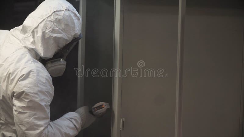 Man painting with spray paint gun in workshop. Clip. Industrial metal coating. Man in protective suit, wearing a gas stock photography