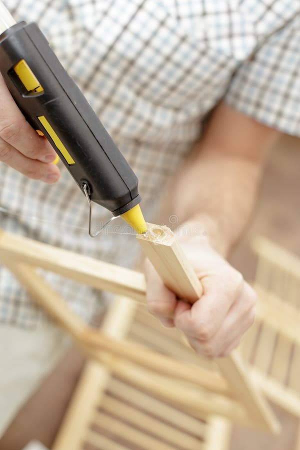 Man putting an electric hot glue gun for wooden furniture stock photos