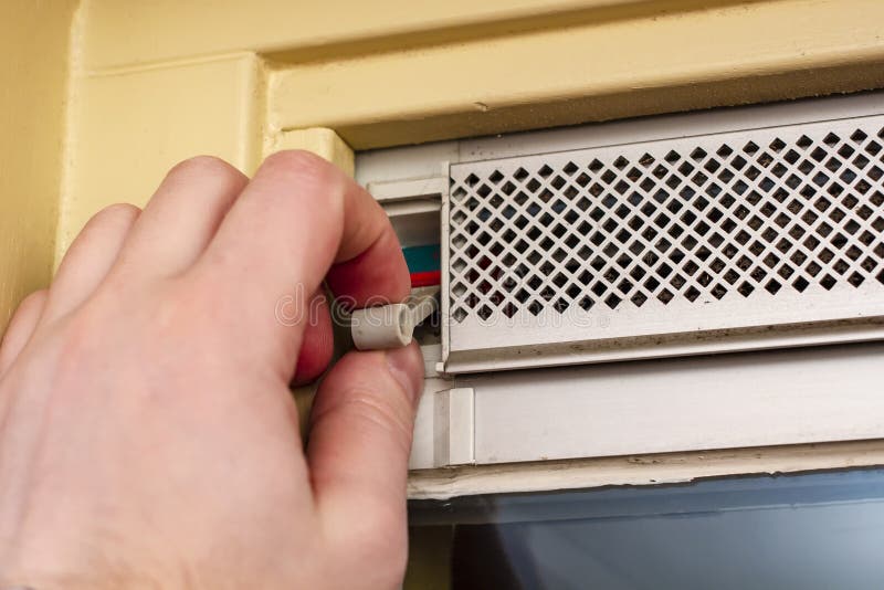 A man`s hand closes the inlet vent adjustable valve over the airtight window after the room in the house has aired stock image