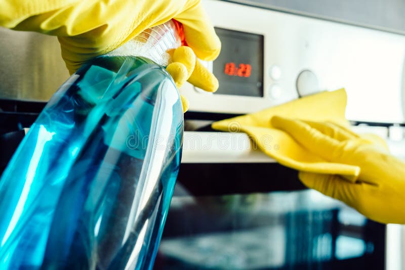 Man`s hand in glove with rag cleaning oven. Man`s hand in yellow rubber glove with rag cleaning kitchen oven royalty free stock image