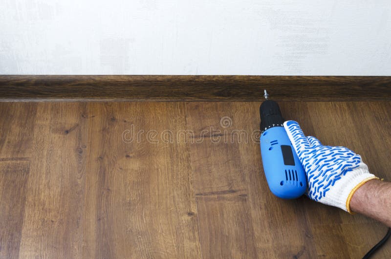 Man using a screwdriver for floor skirting board,plinth.Concept of repair.Empty space for text royalty free stock photography