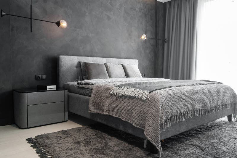 Master bedroom for a lonely stylish man, a bachelor. Modern room with trendy gray interiors, large king-size and lamps. stock image