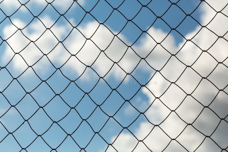 Metal mesh netting on the blue sky background and clouds.  stock images