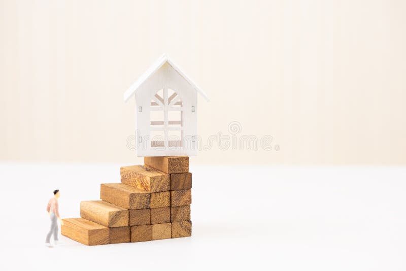 Miniature people small figure walking to model white house on wood block stacking step stair. Property investment. And house mortgage financial concept, Home royalty free stock photo