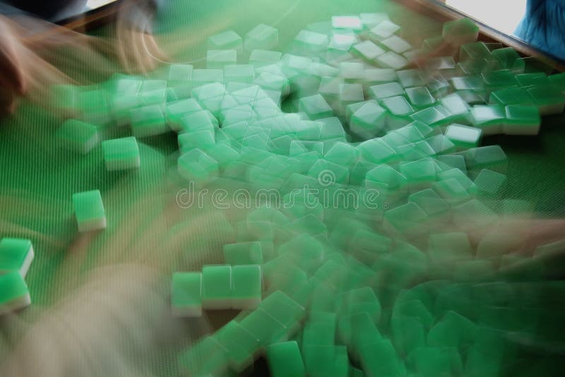 Shuffling Mahjong Tiles. Four players mix green Mahjong tiles in preparation for another turn or round stock photography