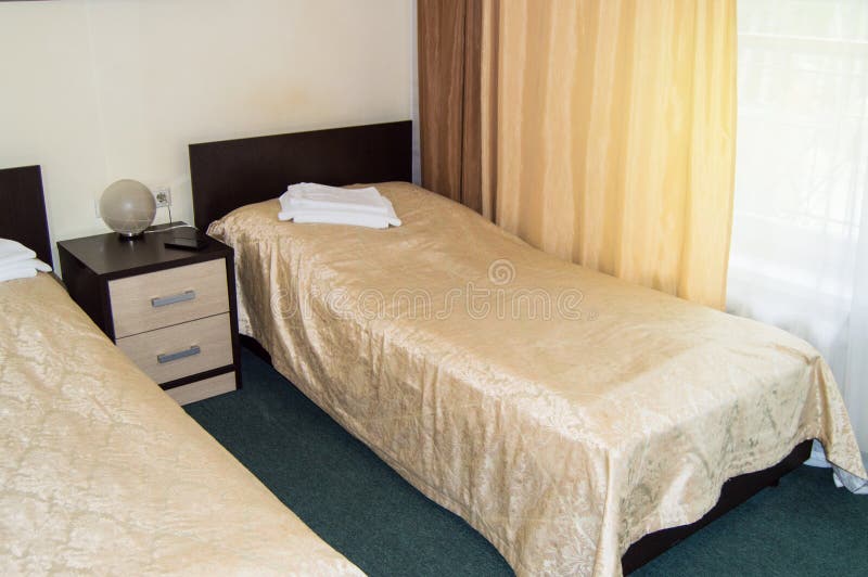 Modern double room with two single beds, bedside table, towels and table lamp, cozy inexpensive room for travelers, good service. Double room with two single stock photo