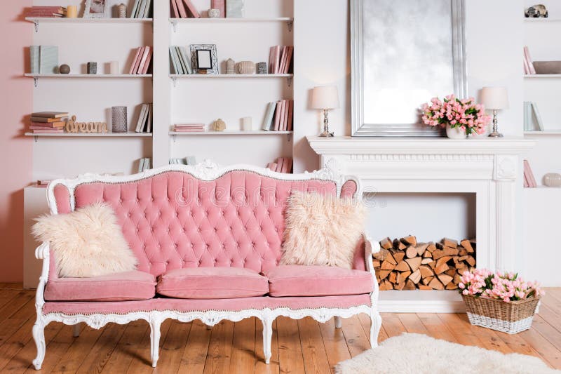 Modern light interior with fireplace, spring flowers and cozy pink sofa.  royalty free stock photography